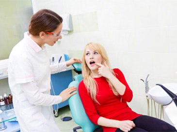 woman pointing at her mouth to dentist