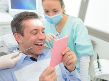 man with dental assistant looking at smile